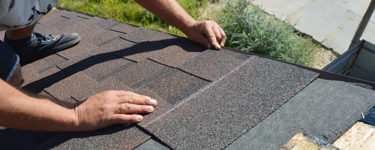 Roofer installing asphalt shingles on house