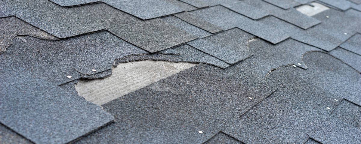 Torn asphalt shingles and roof damage requiring repair