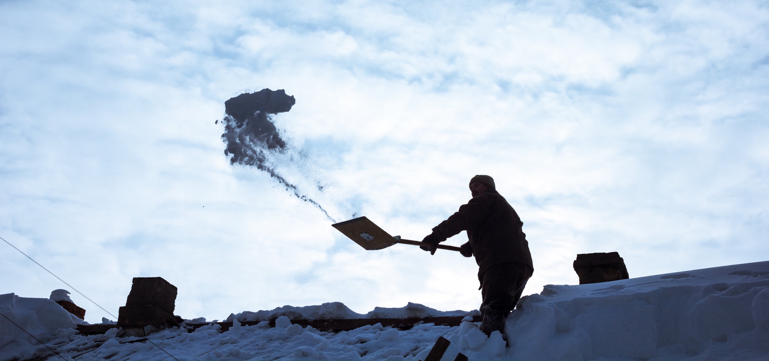 Man shovelling snow off a roof